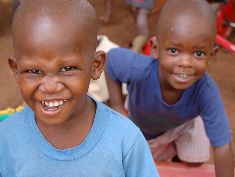 two young boys smiling and getting their picture taken while playing