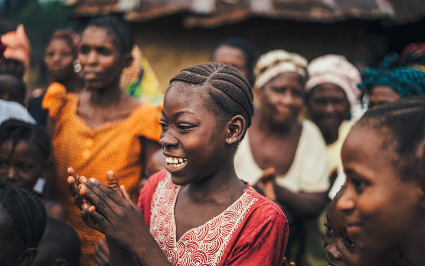 a group of young women smiling and clapping in a developing country