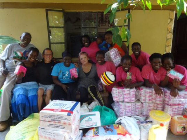 a group of volunteers smiling and posing in front of a stock of household supplies
