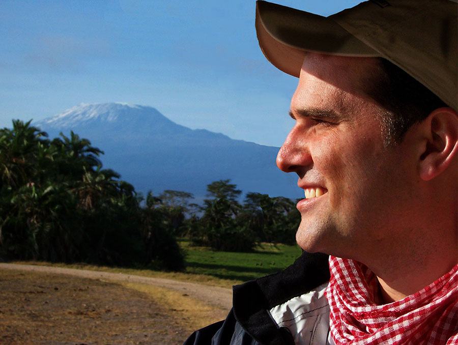 Ryan Snider posing and smiling by Kilimanjaro