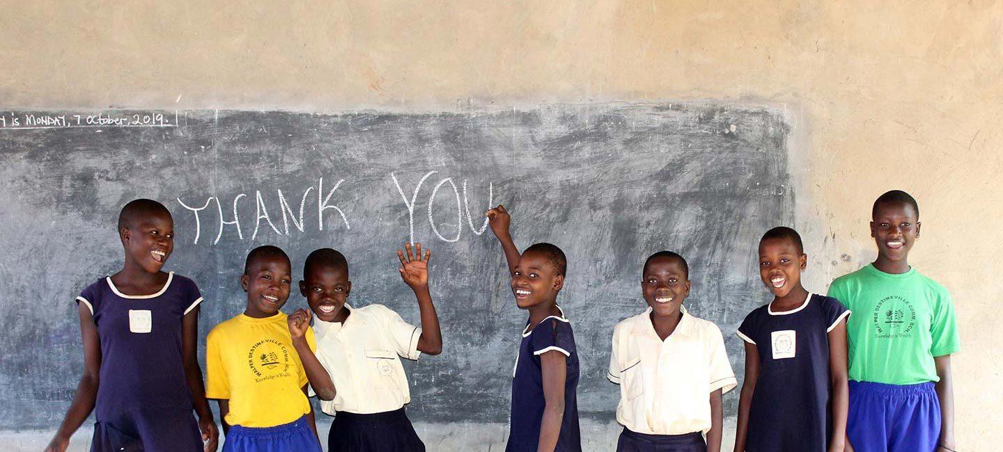 a group of young boys standing in front of a chalkboard wall with the words "thank you" written on it