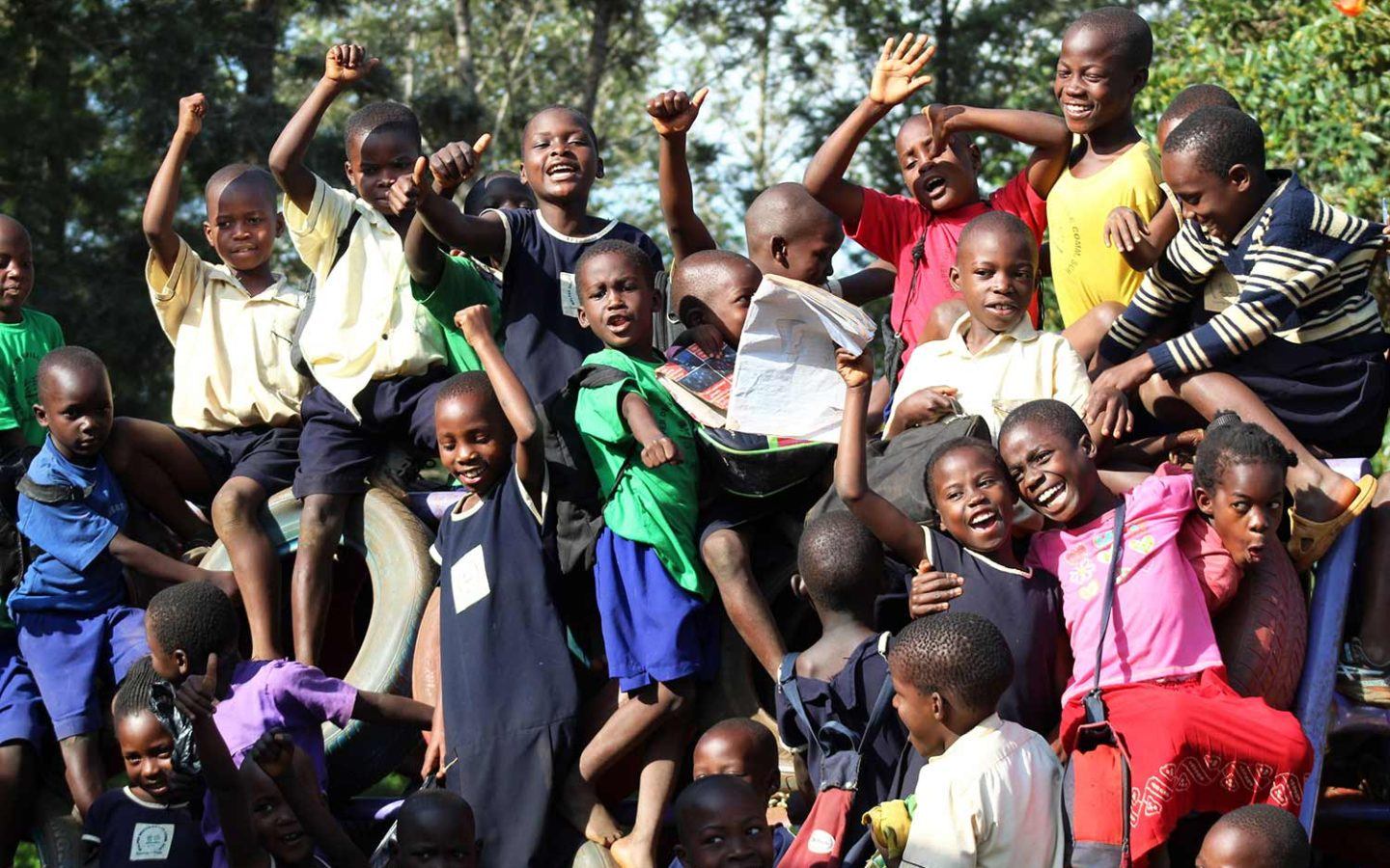 a group of young children smiling and posing for a group shot in a developing country