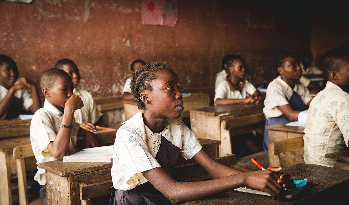 young men and women sitting at desks in their classroom in Kenya