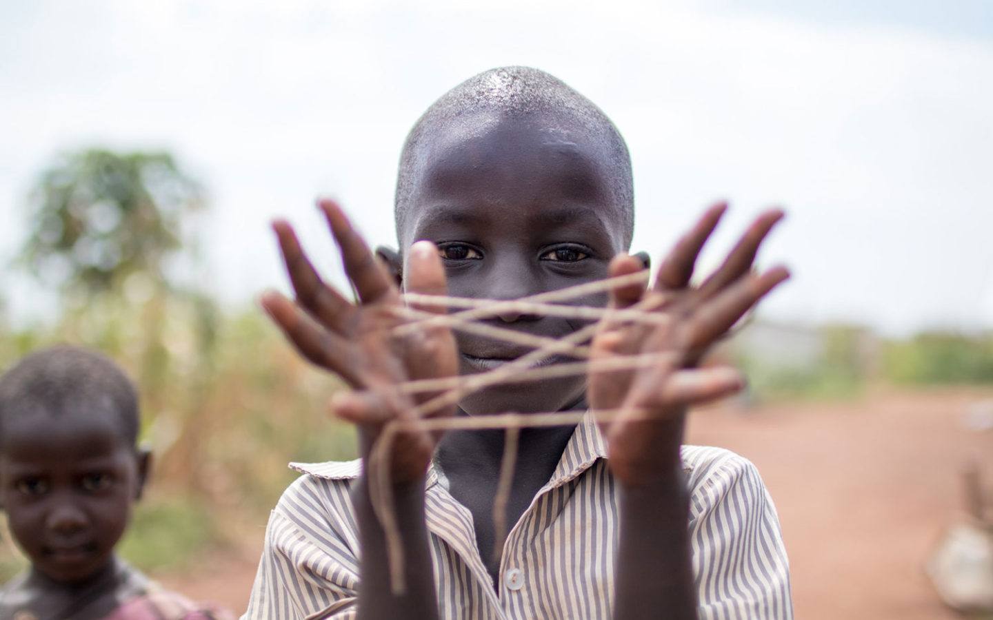 a young boy in Kenya showing a web of string stretched out between his hands