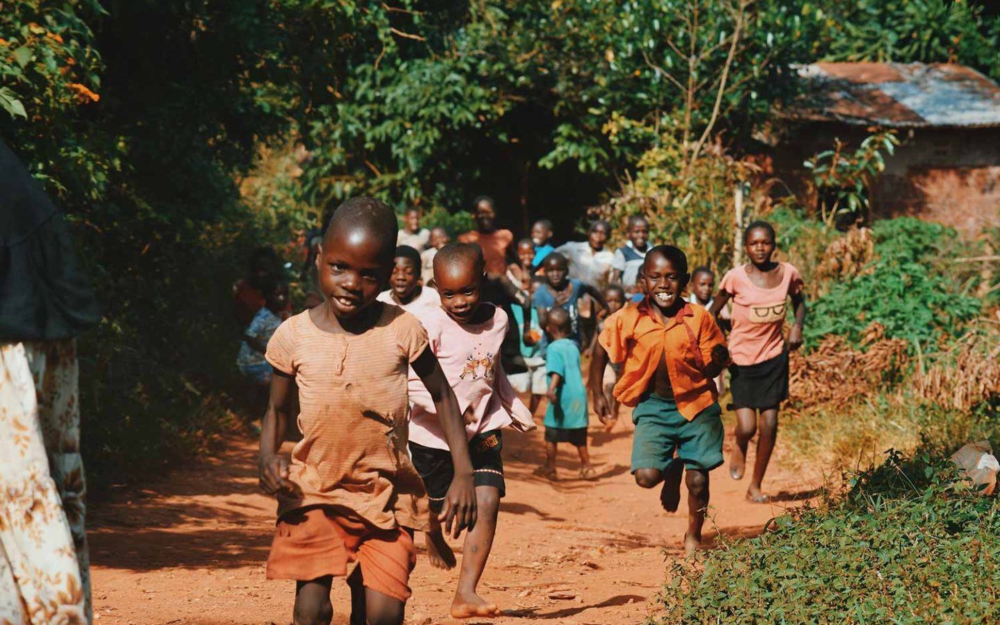 a group of young children in Kenya running down a path and smiling