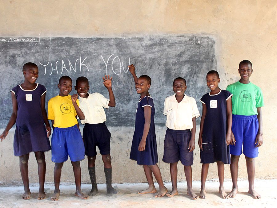 a group of young boys standing in front of a chalkboard wall with the words "thank you" written on it