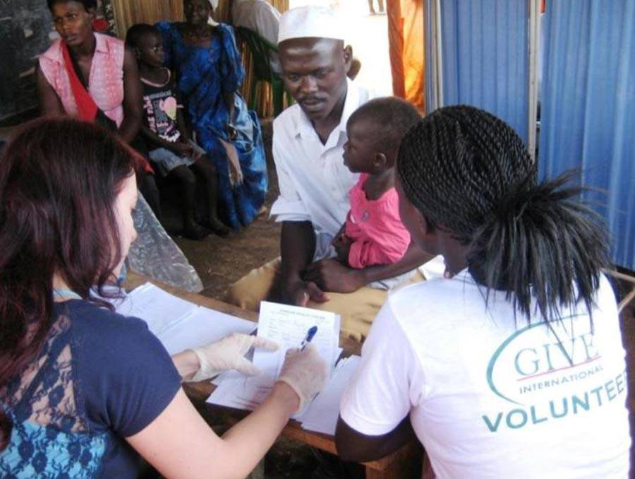 a man sitting with a child and giving information to volunteers in a developing country