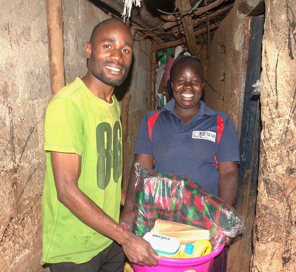 two people holding a container of household supplies for an international support program in Kenya