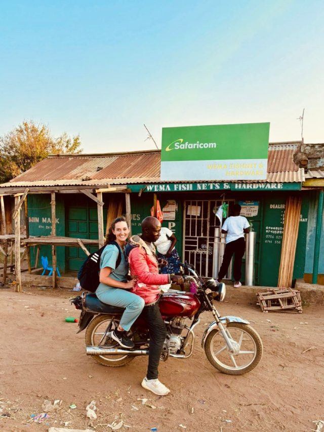 two people on a motorcycle in front of a building
